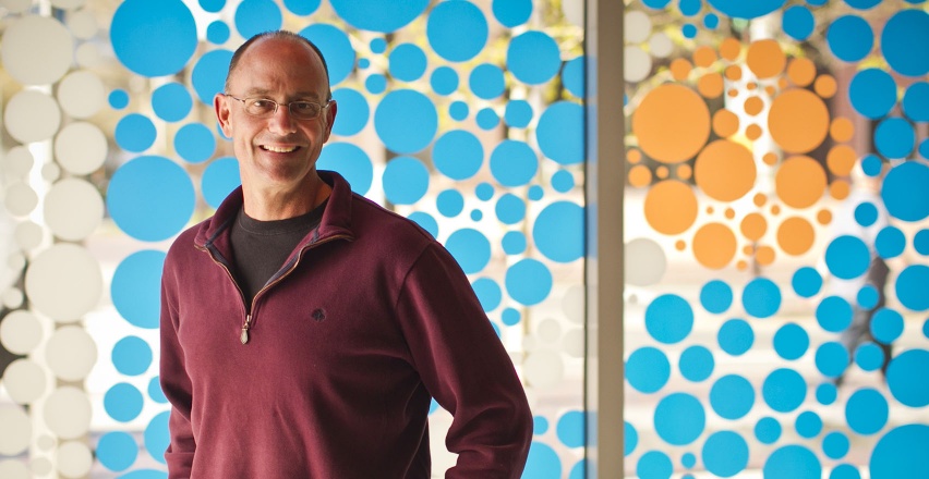 man stands in front of window with blue and orange dots