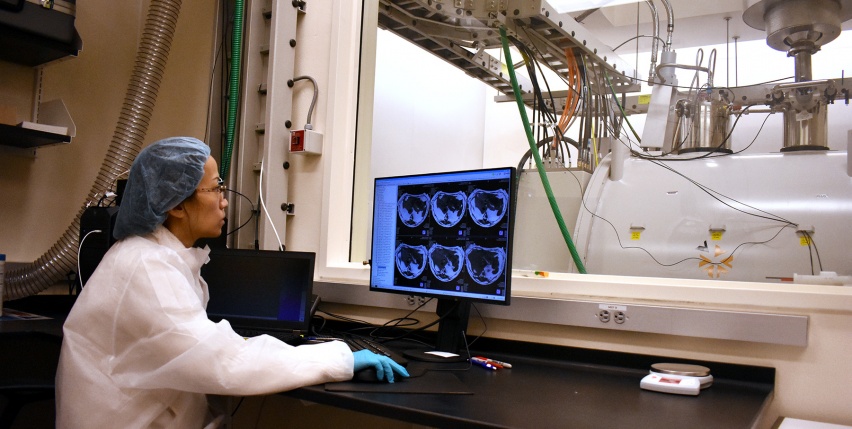 Researcher at a computer overlooking an MRI machine